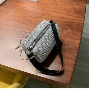 Détail d'un sac cylindre en strass argentés avec chaîne en métal et bandoulière noire