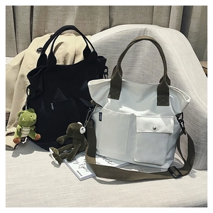 Detail of canvas tote bag with dual front pockets and adjustable crossbody straps