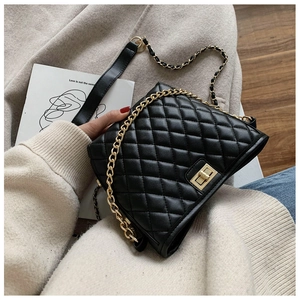 Close-up of black quilted shoulder bag with gold chain strap and metal turn-lock