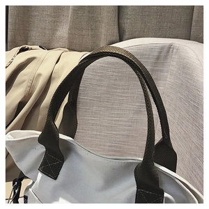 Close-up of durable white canvas tote bag with reinforced brown woven handles