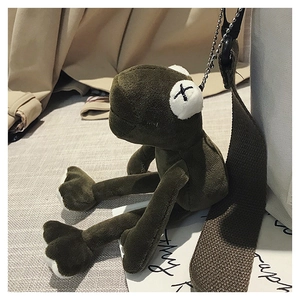 Detail of green plush frog keychain with X eyes on a minimalist canvas tote bag