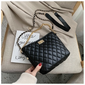 Close-up of black quilted shoulder bag with gold chain strap and turn-lock closure