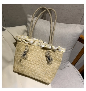 Detail of beige straw tote bag with daisy floral ruffle trim and woven handles