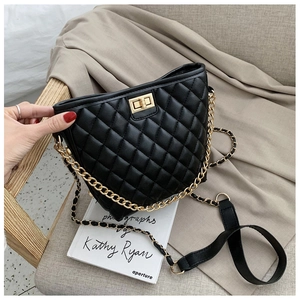 Detail of black quilted leather shoulder bag with gold chain strap on a wooden chair