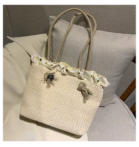 Detail of straw tote bag featuring yellow gingham sunflower trim and blue tassels