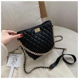 Detailed shot of black quilted bag with golden twist-lock and metal chain strap