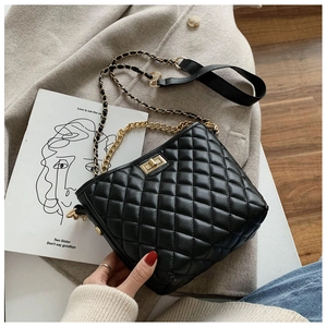 Close-up of black quilted shoulder bag with gold square twist lock and chain strap