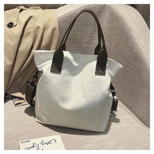 Detailed view of white canvas tote bag with dark brown handles and detachable strap