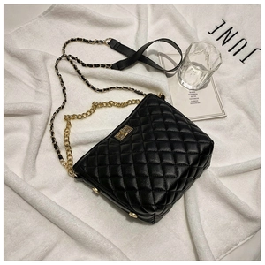 Detail of black quilted leather shoulder bag with gold chain strap and metal clasp