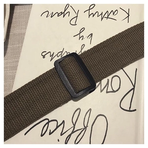 Close-up of brown woven strap with black adjustable buckle on a canvas tote bag