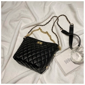 Detail of black quilted leather shoulder bag with gold chain strap and turn-lock closure