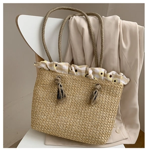 Detail of straw woven tote bag with yellow floral frill and braided rope handles