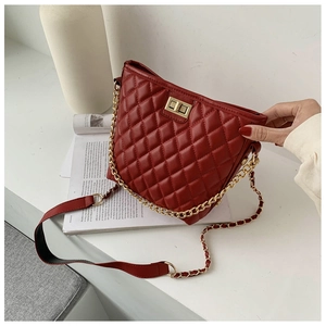 Detail of burgundy quilted crossbody bag with golden chain strap and turn-lock closure