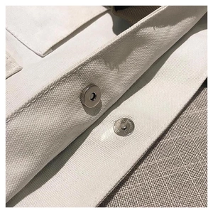 Macro detail of metal magnetic buckle closure on durable white canvas tote bag