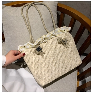 Detail of straw tote bag with daisy ruffle trim and woven rope handles on a wooden chair