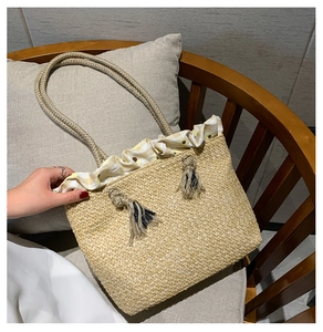 Detail of straw tote bag with yellow gingham ruffles, tassels, and rope handles