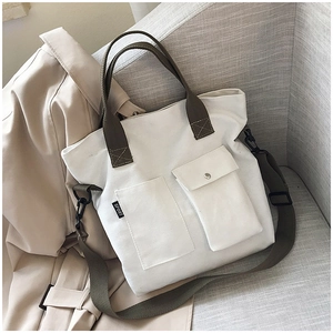 Detail of off-white canvas tote with green straps, front pockets, and a SPORT label