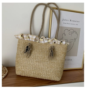 Detail of straw woven tote bag featuring sunflower pattern fabric and braided rope handles