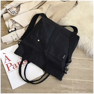 Detail of black canvas tote bag with dual front pockets and adjustable shoulder straps