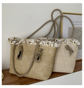 Detail of straw tote bag showing sunflower print fabric and rope handles for beach