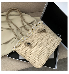 Close-up of woven straw tote bag with floral ruffle trim and thick rope handles