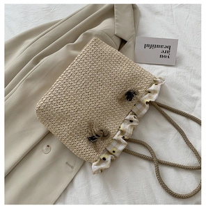 Detail of straw tote bag with yellow floral frill trim and beige tassel charms
