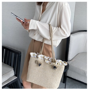 Detail of straw tote bag featuring yellow floral ruffle trim and thick cotton rope handle