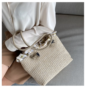 Detail of straw woven tote bag featuring floral lining and braided rope handle
