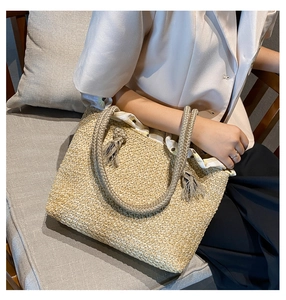 Detail of straw tote bag showing woven texture, rope handles, and floral lining