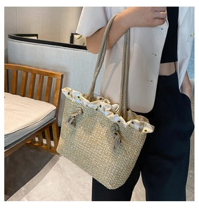 Detail of hand-woven straw tote bag with floral ruffle trim and fringe tassel charm