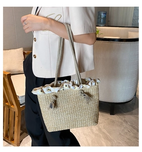 Detail of straw tote bag with sunflower gingham trim and decorative rope tassel