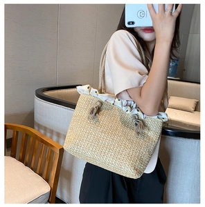 Detail of hand-woven straw tote bag with daisy print lining and decorative tassels
