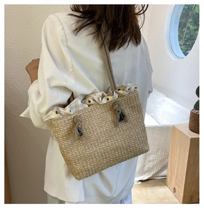 Detail of straw tote bag featuring daisy floral fabric trim and thick rope shoulder strap