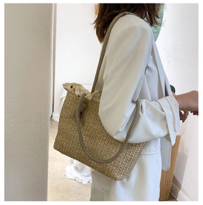 Detail of straw woven tote bag featuring yellow checkered lining and braided rope handle