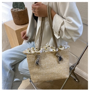 Detail of straw woven tote bag featuring floral sunflower lining and braided rope handles