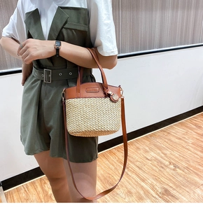 Detail of vintage straw bucket bag with dark brown leather straps and metal tag