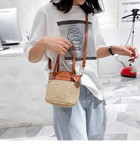 Detail of handmade straw bucket bag with brown leather trim and adjustable shoulder strap