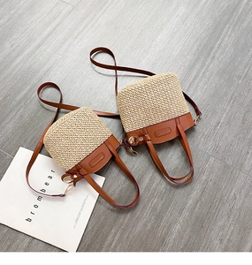 Detail of straw bucket bag with brown leather stitching and adjustable shoulder strap