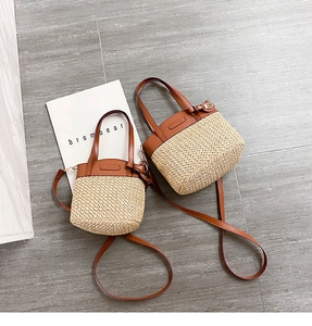 Straw bucket bag detail with brown leather trim, gold hardware and long shoulder strap