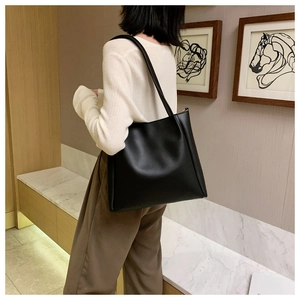 Minimalist black tote bag shown on model highlighting the elegant drape and large capacity