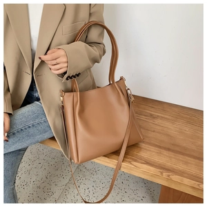 Close-up of khaki leather tote bag with metal buckle on a minimalist background