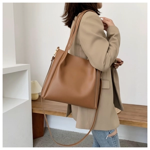 Detail of caramel leather tote bag showing smooth texture and side pleated design