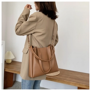 Brown leather tote bag worn with khaki blazer and blue jeans for urban commute