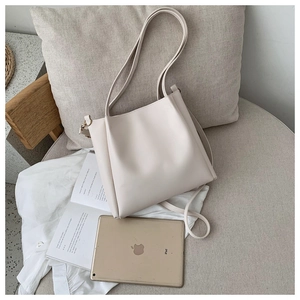 Minimalist beige tote bag shown with a tablet and book on a soft fabric chair