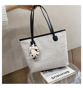 Close-up of canvas tote bag texture with black leather trim and plush cow charm