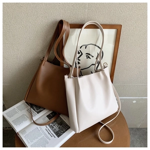 Detail view of large tote bags in brown and beige colors with adjustable shoulder straps
