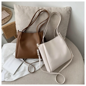 Detail of minimalist leather tote bags in brown and beige with adjustable straps