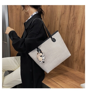 Minimalist grey canvas tote bag with black leather straps and cow print charm detail