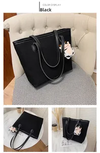 Detail of black canvas tote bag with leather straps and cute cow plush pendant charm