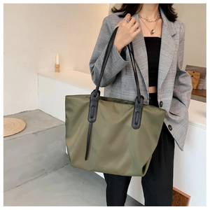 Olive nylon tote bag with black leather straps shown on a model for work and commute